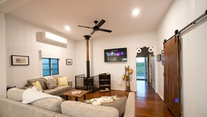 Ein Wohnzimmer mit einer Couch, einem Couchtisch, einem an der Wand befestigten Fernseher und einem Deckenventilator.