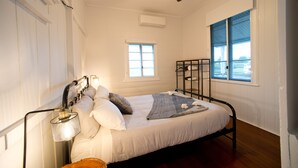 Ein Schlafzimmer mit einem Bett, einem Deckenventilator, einem Fenster und einem Regal mit Handtüchern.