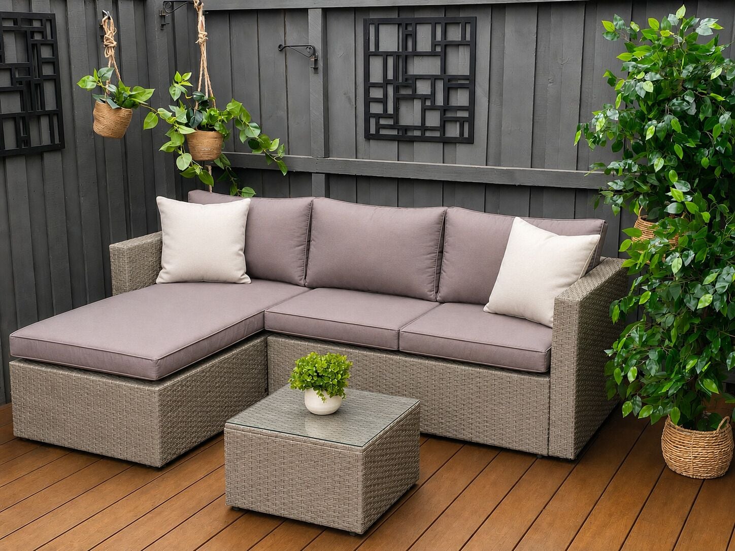A sectional sofa with cushions, a small side table, and hanging planters against a wooden wall.
