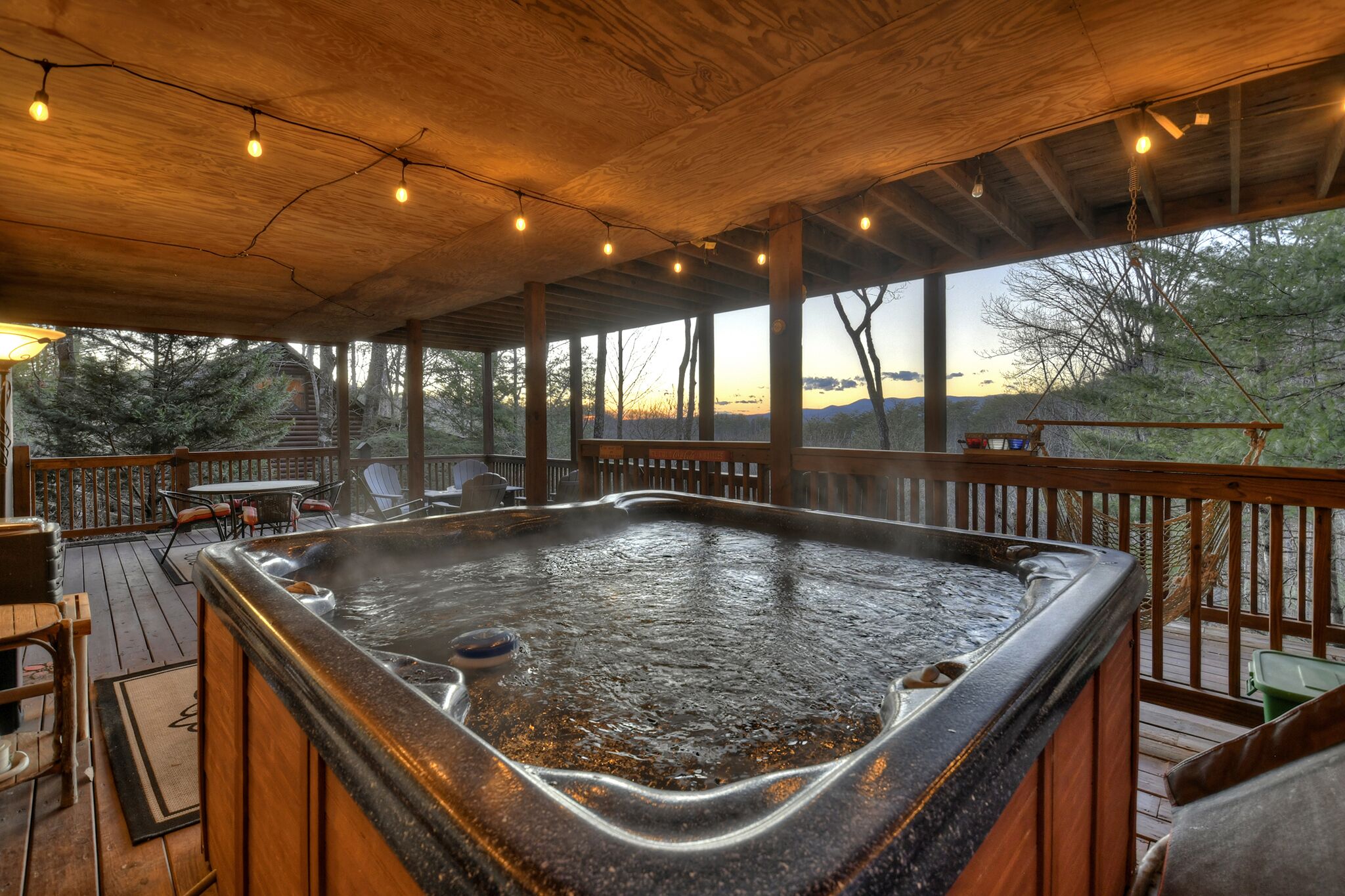 Un bain à remous sur une terrasse en bois, avec vue sur les arbres et les collines.