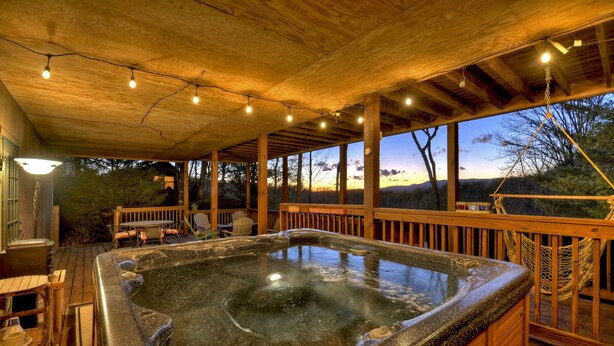 A hot tub area with a wooden deck, outdoor seating, and a view of the landscape. - Overlook Oasis - Hot tub, firepit, and comfy king beds! (Blue Ridge)