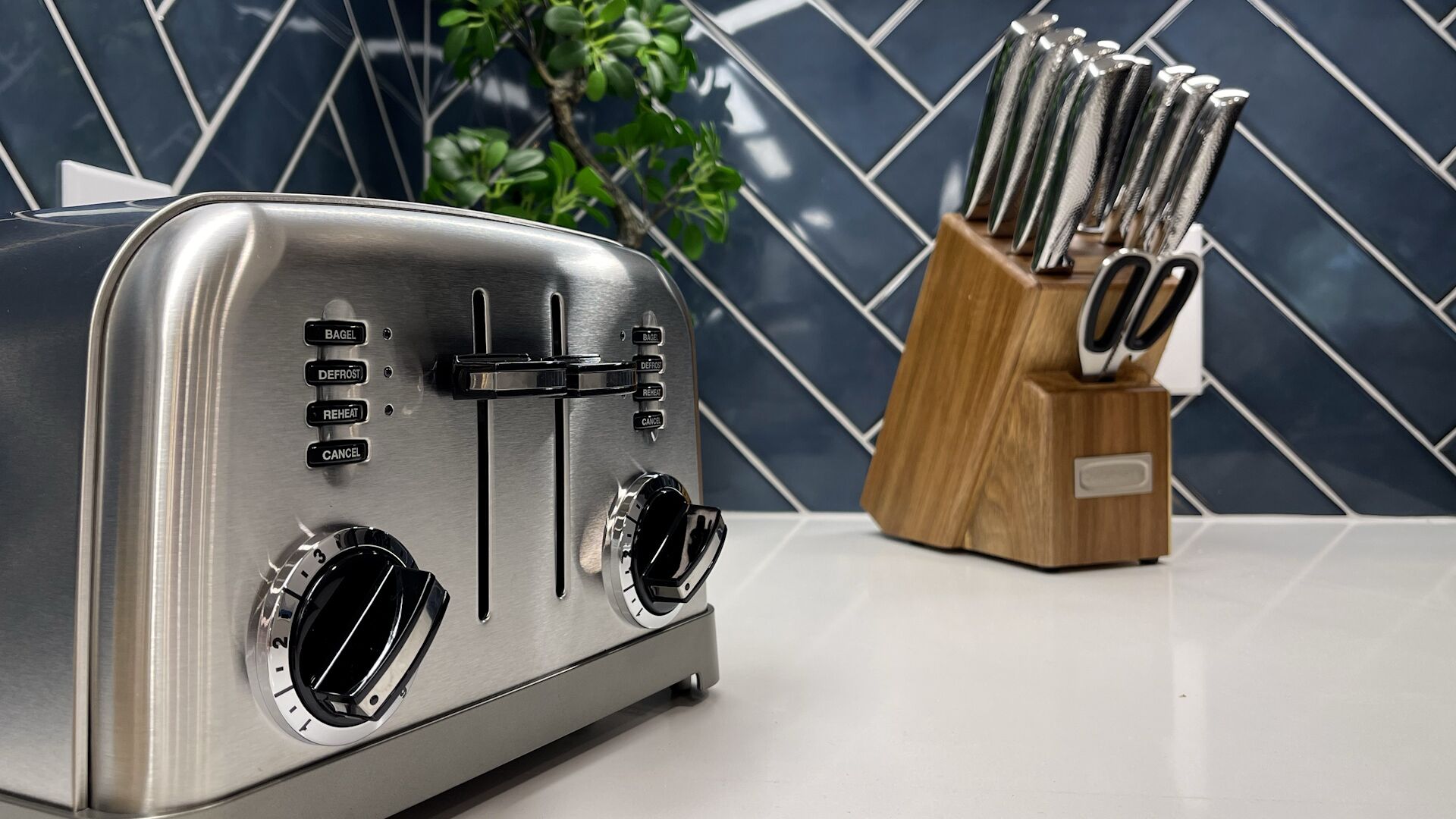 A stainless steel toaster with multiple settings and a wooden utensil holder with knives.