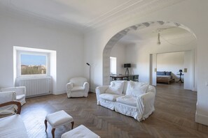 A spacious living room with a herringbone floor, white furniture, a large window, and an arched ceiling. - Vittorio Luxury Panoramic Apartment (Roma)