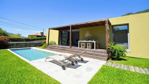 A modern house with a swimming pool, a covered patio, and a dining area.