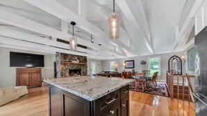 Una cocina amplia con una isla grande, piso de madera y chimenea de piedra.
