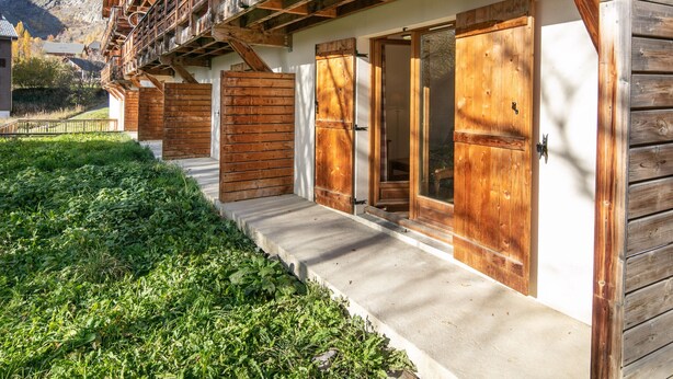 A wooden building with balconies, large wooden doors, and a concrete pathway. - Cosy apt 4/6 ppl, terrace, heated pool (Saint-Sorlin-d´Arves)