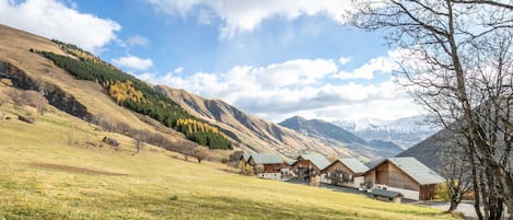 A row of wooden cabins in a mountainous area with a clear sky.