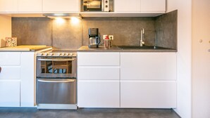 A modern kitchen with white cabinets, stainless steel appliances, a coffee maker, and a microwave. - Spacious apt 7 ppl, mountain view balcony (Saint-Sorlin-d´Arves)