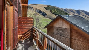 Eine Holzhütte mit einem Balkon mit Blick auf eine Berglandschaft.