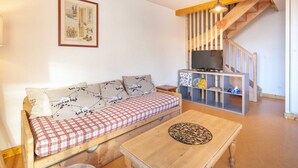 A cozy living room with a wooden sofa, a coffee table, and a TV on a wooden stand.