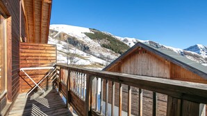 A wooden cabin with a balcony overlooking a snowy mountain landscape.