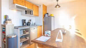 A compact kitchen with wooden cabinets, a microwave, a refrigerator, and a wooden countertop.