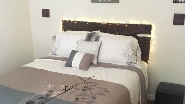 Un dormitorio con cama, mesitas de noche, un letrero en la pared y una mesita auxiliar.