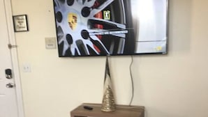 Un televisor montado en la pared sobre un aparador de madera con un cono decorativo encima.