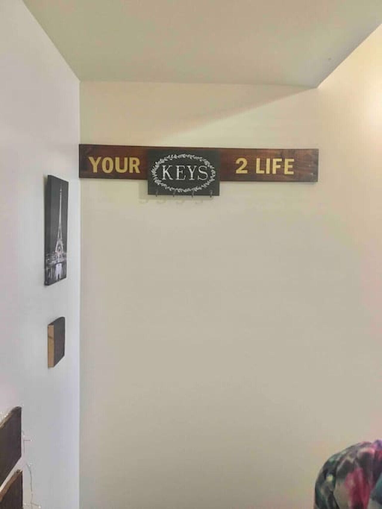 A wall with a sign that reads "YOUR KEYS 2 LIFE" and a framed picture of the Eiffel Tower.