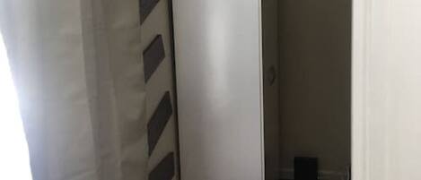 Un pasillo estrecho con una puerta blanca, piso de madera y un diseño decorativo en la pared.