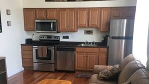 Una cocina moderna con armarios de madera, electrodomésticos de acero inoxidable y un sofá de cuero marrón en una sala de estar.
