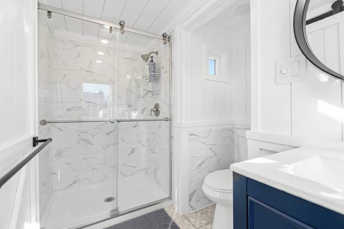 A bathroom with a glass-enclosed shower, a white toilet, and a blue vanity.