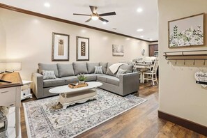 A living room with a grey sofa, a coffee table, a patterned rug, and framed artwork on the walls.