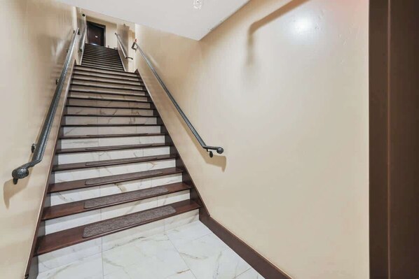 A staircase with marble steps and metal handrails, leading to a door at the top.