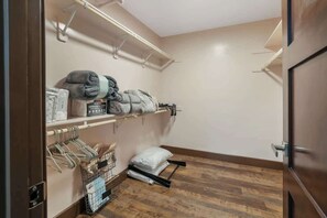 A small, neatly organized closet with shelves, a hanging rack, and a storage bin. - Chic Downtown Loft w/ City Views & Workspace (Visalia)