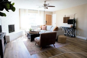 A living room with a sofa, armchair, coffee table, and a fireplace.
