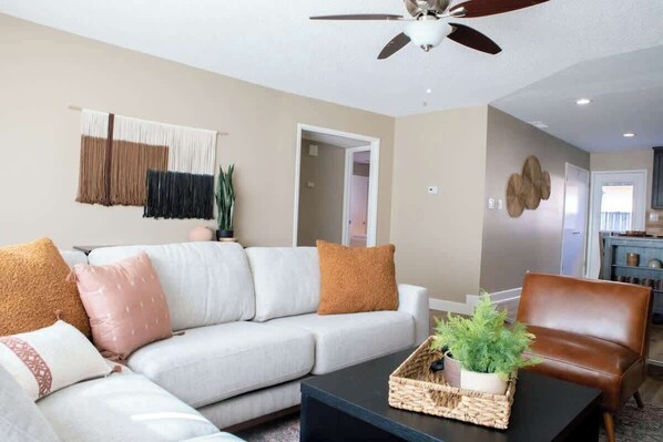 A living room with a sofa, coffee table, and a ceiling fan.