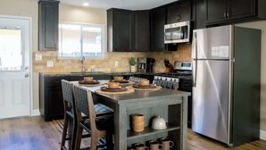 A modern kitchen with dark cabinets, stainless steel appliances, and a central island with seating.