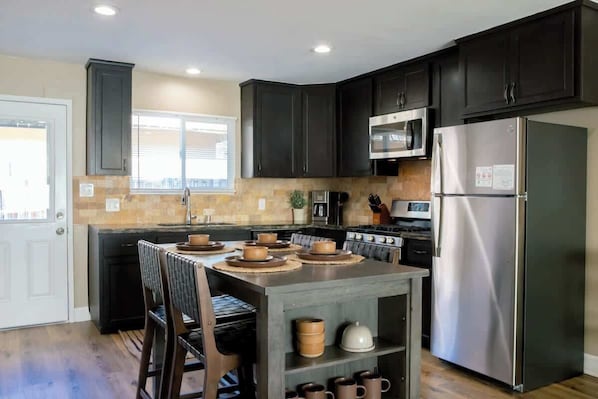 A modern kitchen with dark cabinets, stainless steel appliances, and a central island with seating.