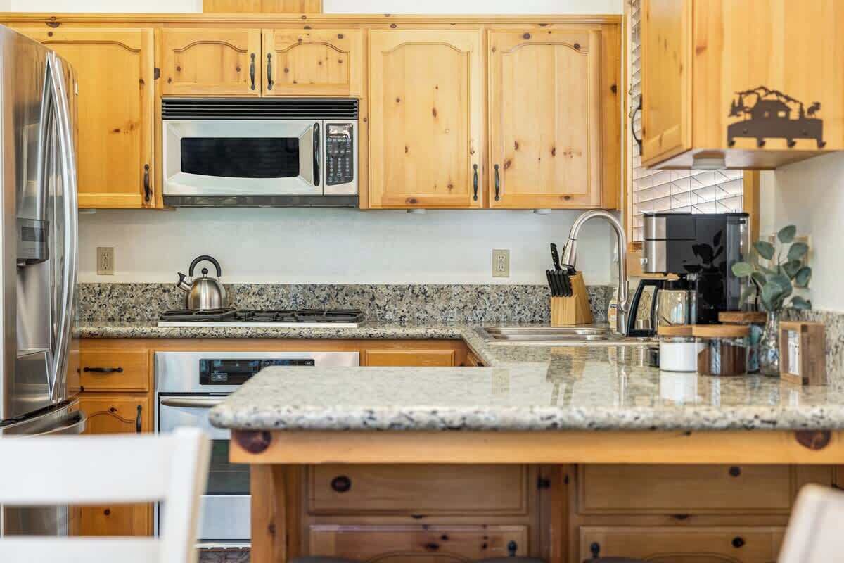 A kitchen with wooden cabinets, stainless steel appliances, granite countertops, and a sink.