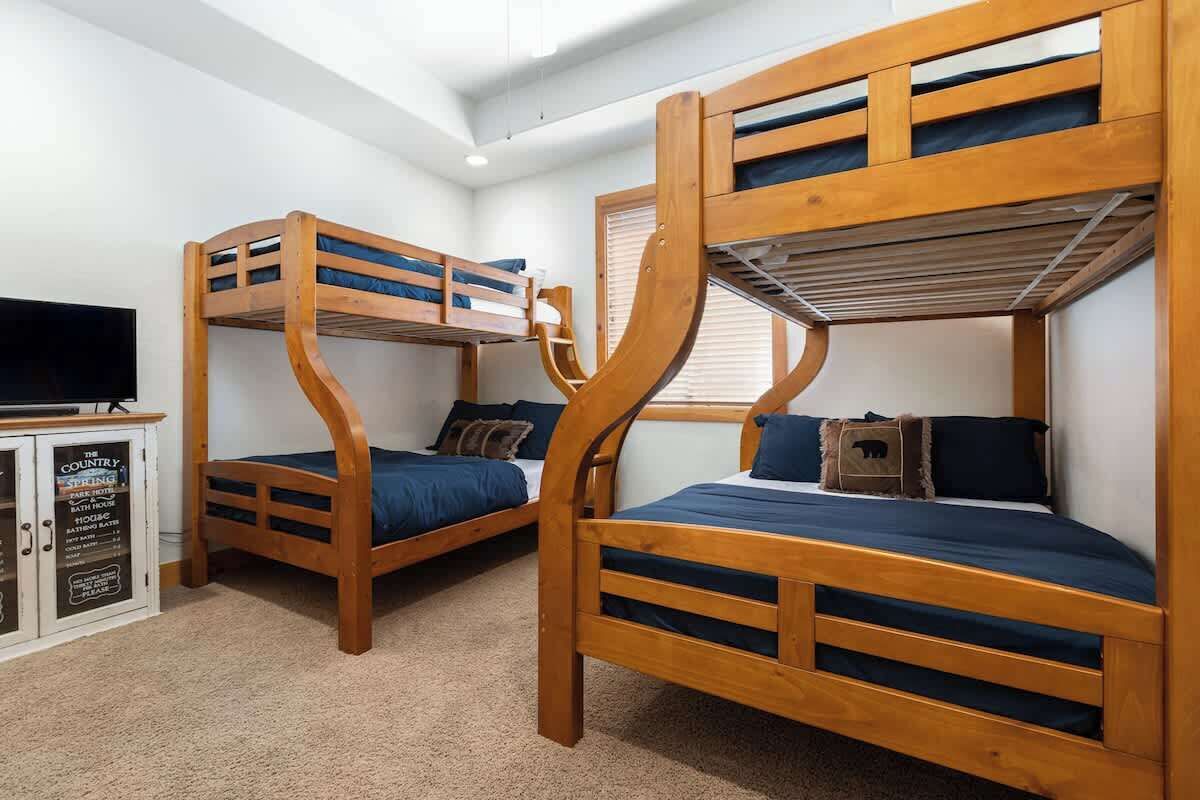 Une chambre avec deux lits superposés, une télévision et un placard sur lequel est apposée une pancarte.