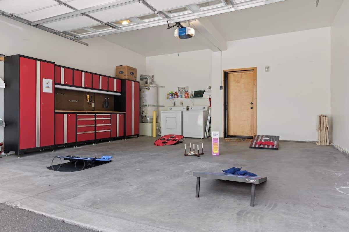 A spacious indoor area with a red and black storage unit, a white cabinet, and a wooden door.