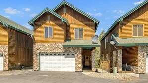 A two-story log cabin with a stone foundation, a garage, and a covered porch.