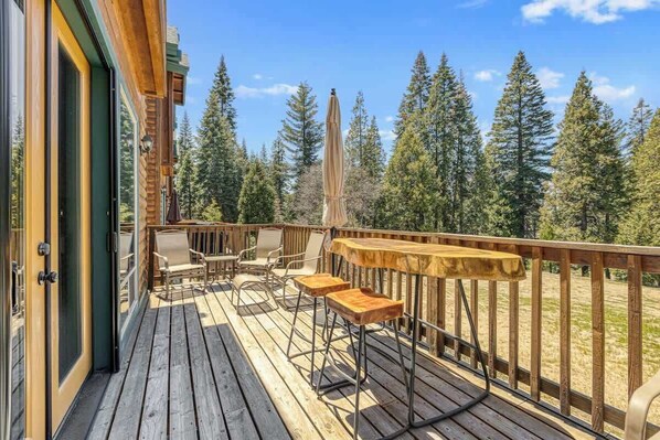 Relax on the deck with a seating area featuring two chairs and a table, surrounded by a railing overlooking the forest.