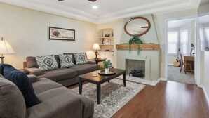 Ein Wohnzimmer mit einer Couch, einem Couchtisch, einem Kamin und einem Deckenventilator.