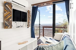 Een kamer met een aan de muur bevestigde televisie, een bank en uitzicht op het landschap.