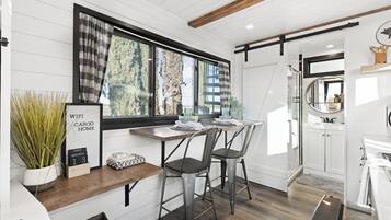 A modern kitchen with a wooden countertop, two bar stools, a window with curtains, and a sign indicating a WiFi-enabled home.
