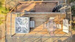 A wooden deck with a hot tub, seating area, and a spiral staircase.