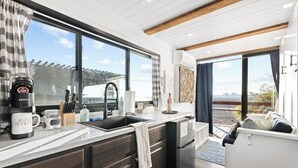 A modern kitchen with a large window, a coffee maker, and a sink.