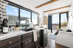 A modern kitchen with a large window, a coffee maker, and a sink. - Tiny Cargo Home, Farm Experience with Rooftop Views (Tulare)