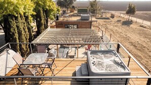 A rooftop terrace with a hot tub, seating area, and a view of the surrounding landscape. - Tiny Cargo Home, Farm Experience with Rooftop Views (Tulare)