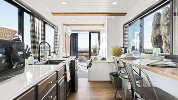 A modern kitchen with a central island, large windows, and a view of the outdoors.