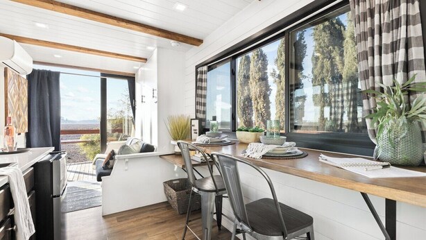 A modern kitchen with a wooden countertop, stainless steel appliances, and a large window with curtains.