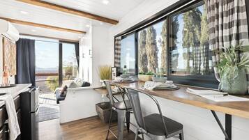 A modern kitchen with a wooden countertop, stainless steel appliances, and a large window with curtains.
