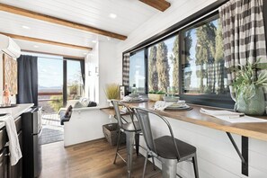 Una cocina moderna con encimera de madera, electrodomésticos de acero inoxidable y un amplio ventanal con cortinas.