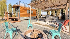 A wooden cabin with a deck, outdoor seating, and a fire pit. - Tiny Cargo Home, Farm Experience with Rooftop Views (Tulare)