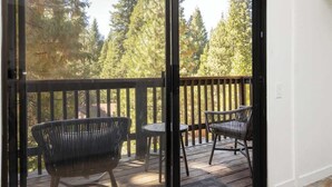 A balcony with a wooden railing, two chairs, and a small table.