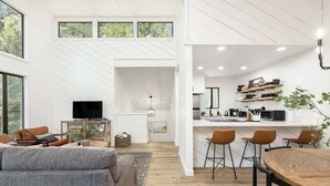A modern living space with a sofa, TV, and dining area.