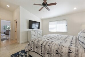 A bedroom with a bed, a ceiling fan, a television on a dresser, and a window with blinds. - Slice of Paradise Steps to Morro Rock (Morro Bay)