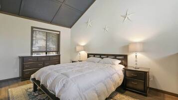 A bedroom with a bed, bedside tables, a window with blinds, and wall decorations.